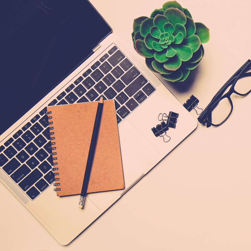 Laptop With Notebook And Glasses On Table