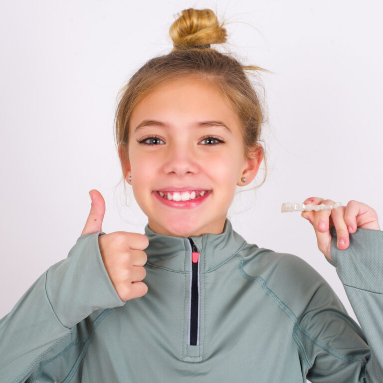 Young Smiling Girl Holding Aligner